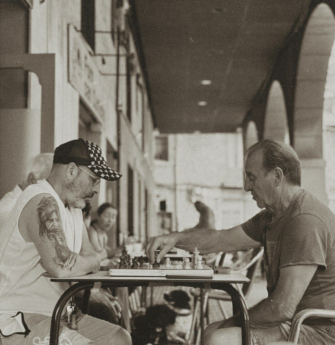 Two elderly men playing chess at a wooden table