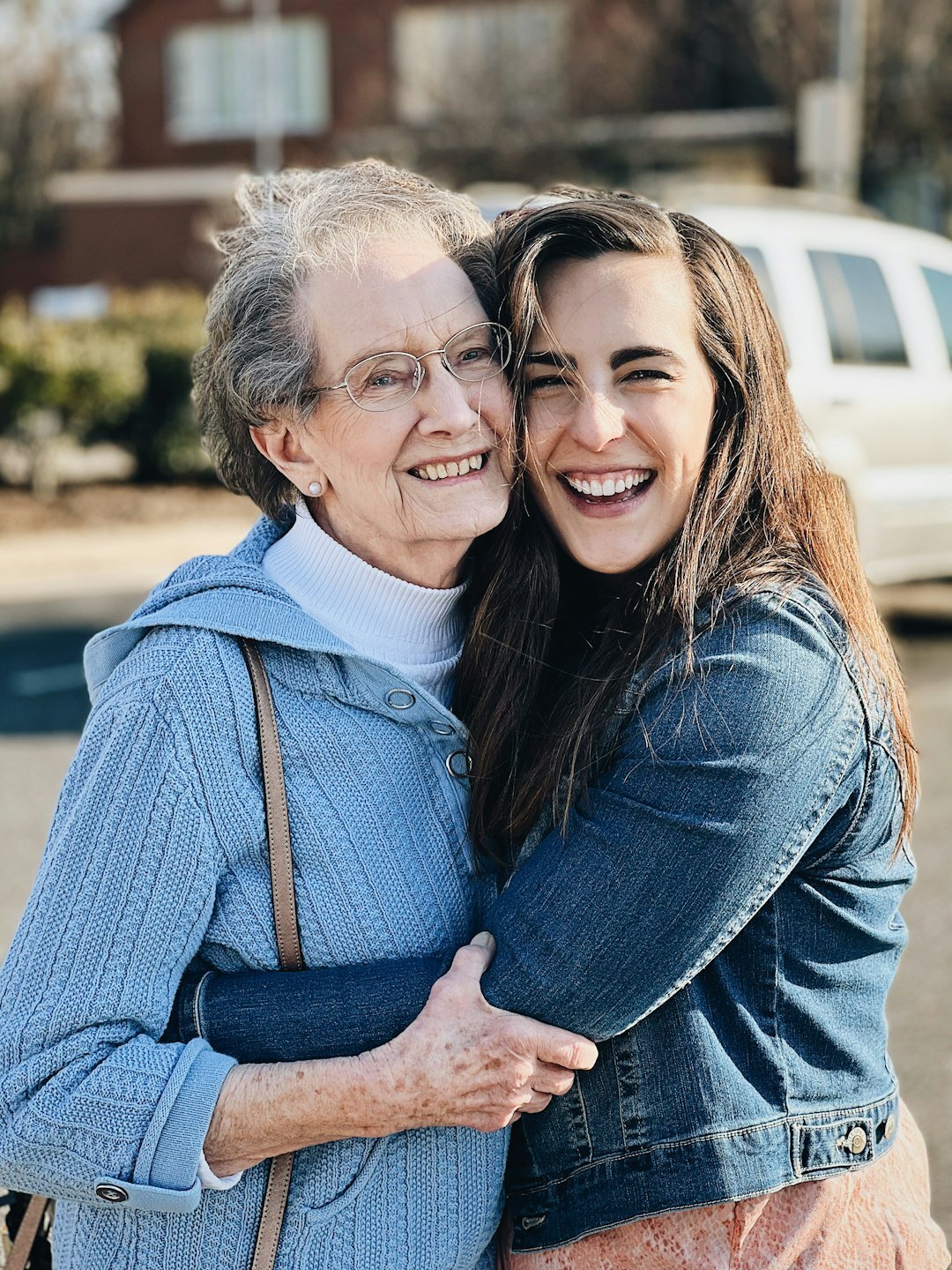Adult daughter visiting and hugging her elderly mother